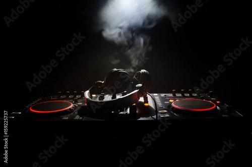 DJ Spinning, Mixing, and Scratching in a Night Club, Hands of dj tweak various track controls on dj's deck, strobe lights and fog, selective focus