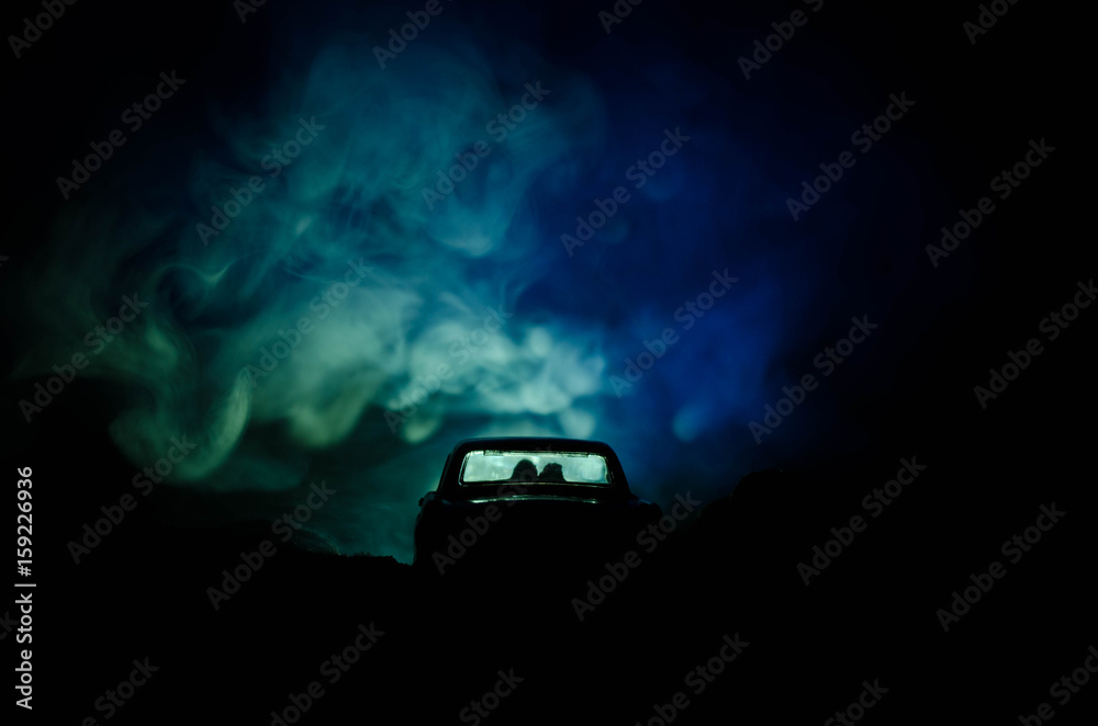 silhouette of car with couple inside on dark background with lights and smoke. Romantic scene. Love concept