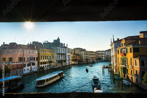 Warm summer day in romantic Venice, Italy. View throught the bridge of Academia with sun reflection