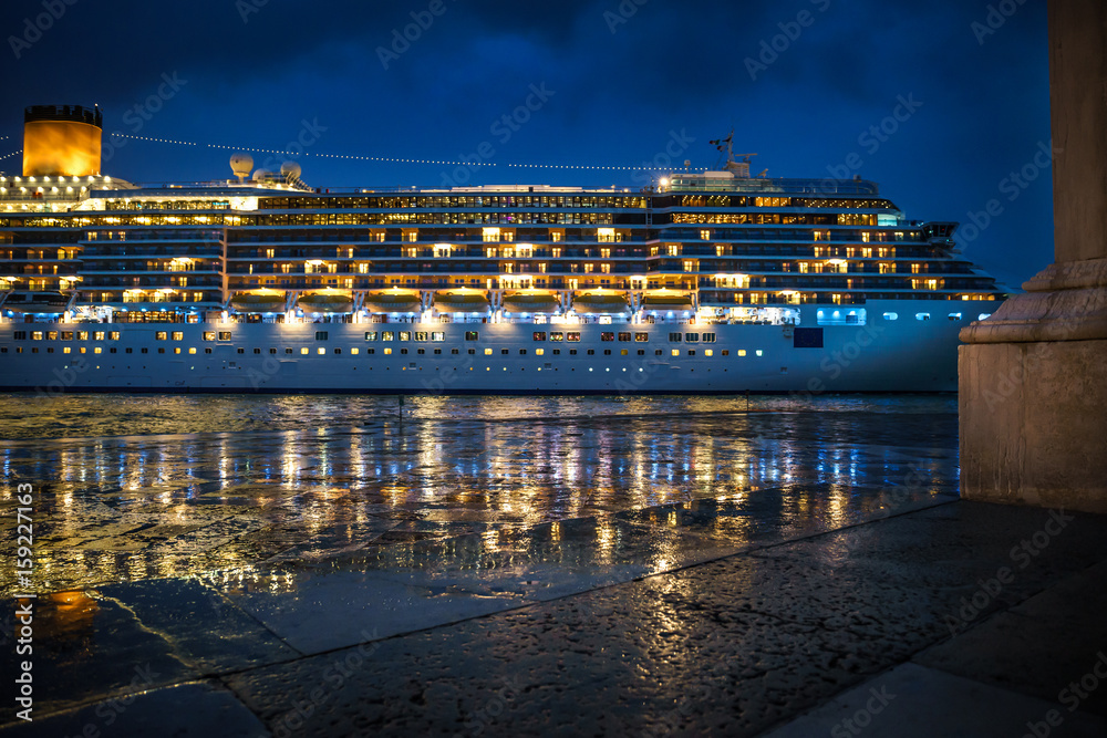 Luxury cruise ship sailing from port on Venice, Italy at night.