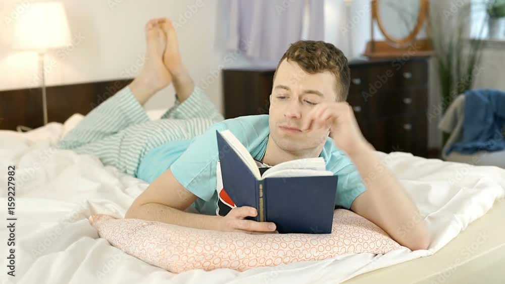 Young man reading book in bed and smiling to the camera, steadycam shot
Young man reading book in bed and smiling to the camera, steadycam shot