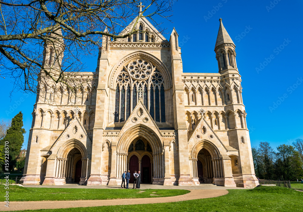 St Albans Cathedral in St Albans, Hertfordshire, England. The priest and students standing and talking outside of the Cathedral and Abbey Church of Saint Albans.