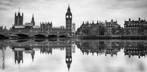 Dramatic, vintage black and white picture of Big Ben and Westminster bridge in London at dusk with blurry reflection in Thames river. photo