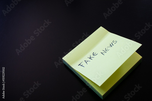 Yellow sticky note with Fake News written on first paper