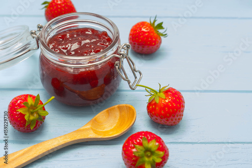 Jar of strawberry jam on blue wooden background