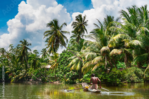 Tropical forest on the river bank .Fisherman floating in a boat.