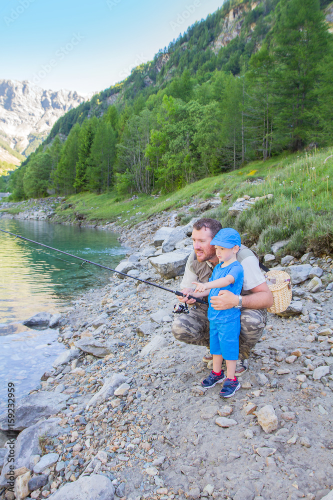 Dad and son are fishing together in a lake in the mountains