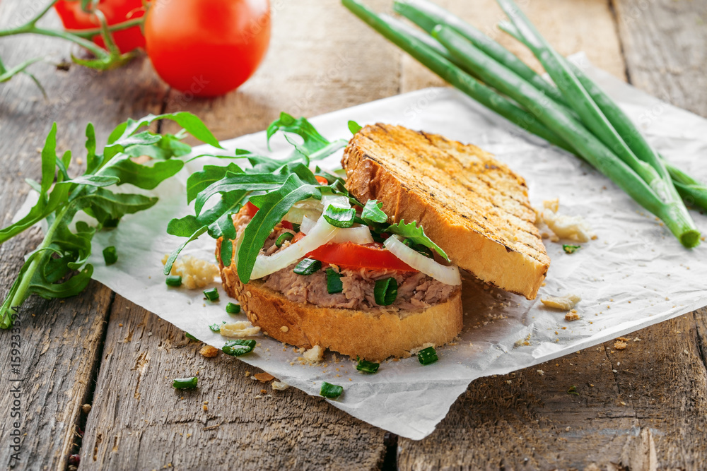 Fish sandwich made of grilled toast, tuna salad and vegetables on a rustic wooden table. Delicious healthy diet meal. Fish sandwich made of grilled toast, tuna salad and vegetables on a rustic wooden table. Delicious healthy diet meal.