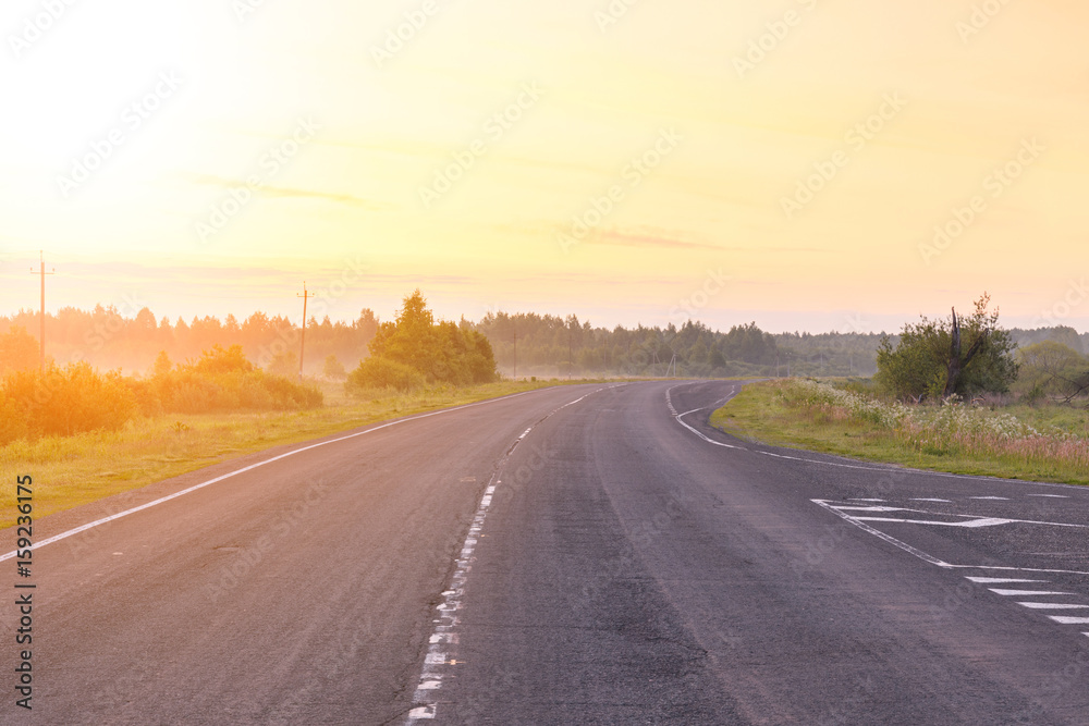 New road in the mist during sunrise in summer