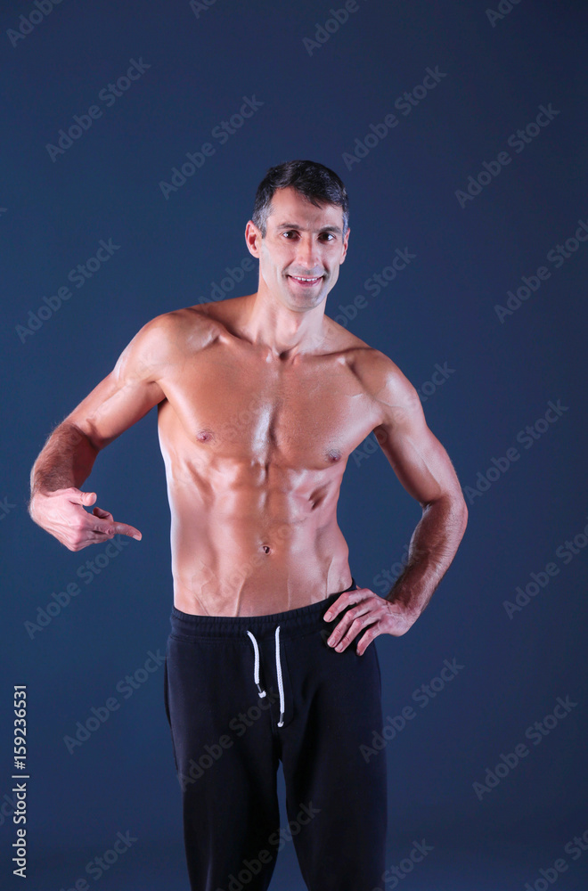 Strong athletic man standing on black background