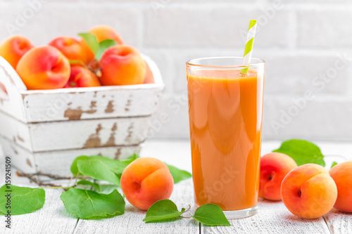 Fototapeta Naklejka Na Ścianę i Meble -  Apricot juice and fresh fruits with leaves