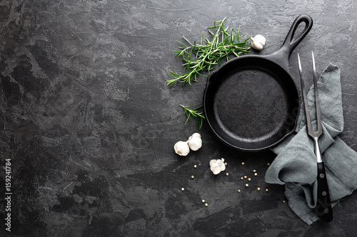 Fotografie, Obraz Empty cast iron frying pan on dark grey culinary background, view from above