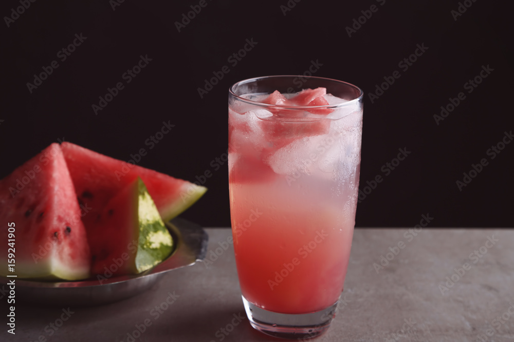 Homemade refreshing drink in glass and plate with watermelon slices on table Homemade refreshing drink in glass and plate with watermelon slices on table