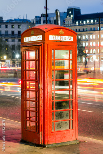 Red telephone box in street with historical architecture in London.