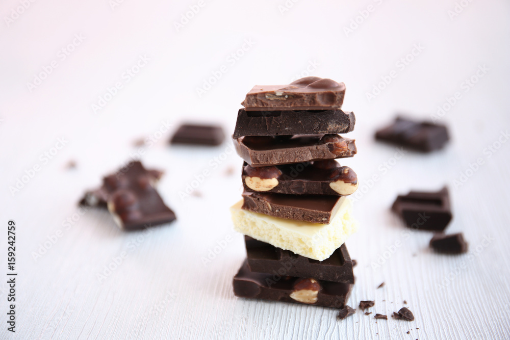 Broken chocolate pieces with nuts on table Broken chocolate pieces with nuts on table