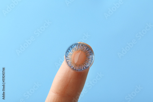 Contact lens on female finger against light background, closeup
