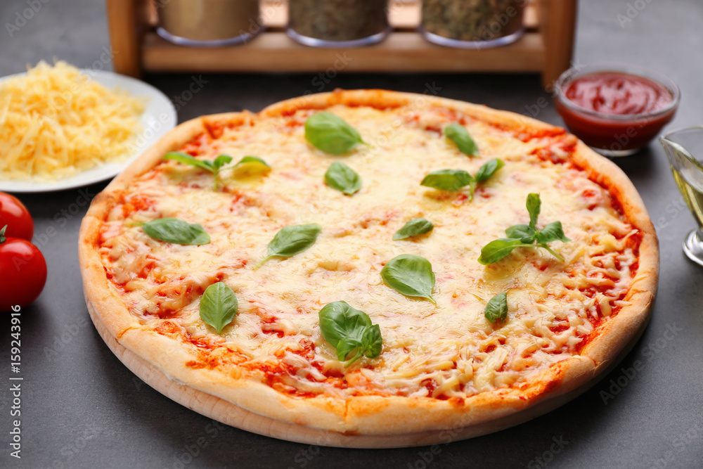 Delicious pizza with melted cheese and basil on table