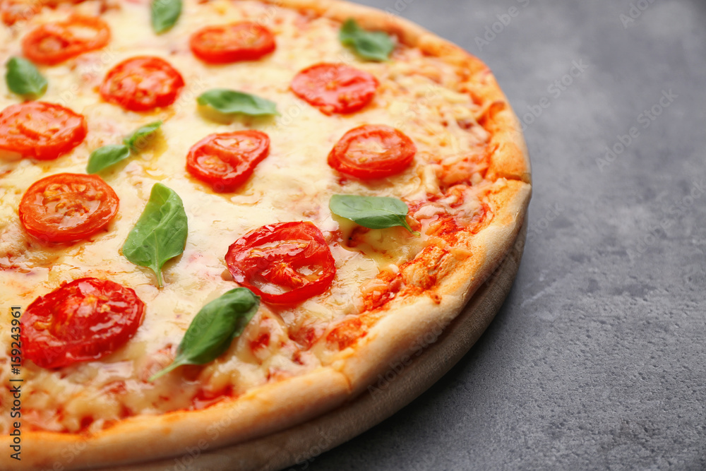 Delicious pizza with tomatoes, basil and melted cheese on grey background Delicious pizza with tomatoes, basil and melted cheese on grey background