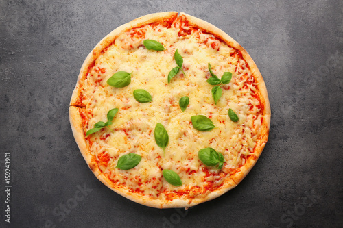 Delicious pizza with melted cheese and basil on grey background