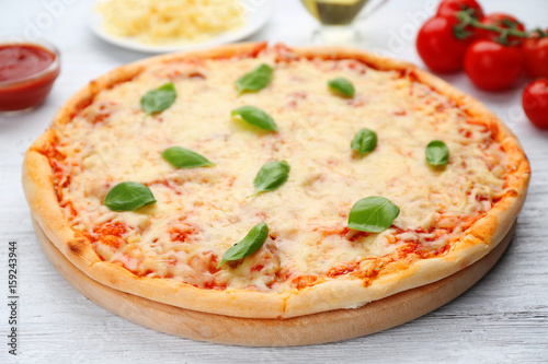 Delicious pizza with melted cheese and basil on wooden table