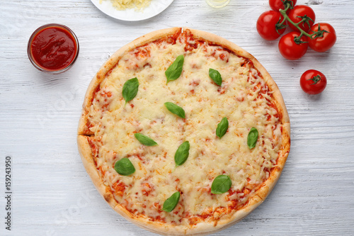 Delicious pizza with melted cheese and basil on wooden table