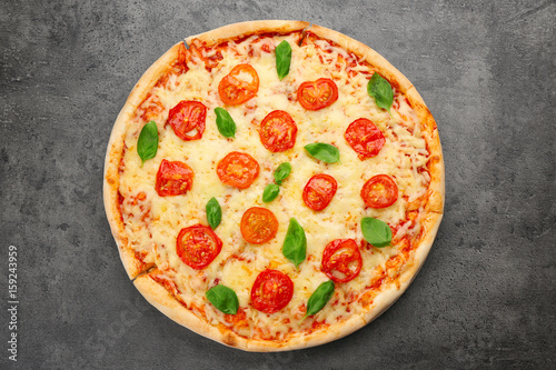 Delicious pizza with tomatoes, basil and melted cheese on grey background