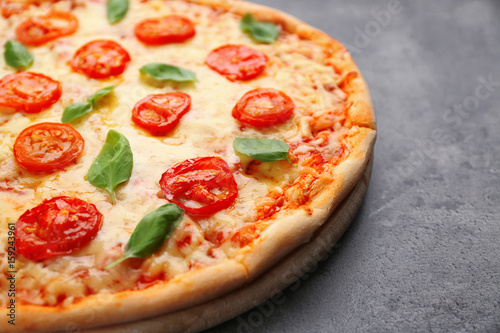 Delicious pizza with tomatoes, basil and melted cheese on grey background