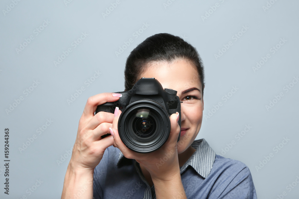 Portrait of beautiful young photographer on grey background Portrait of beautiful young photographer on grey background