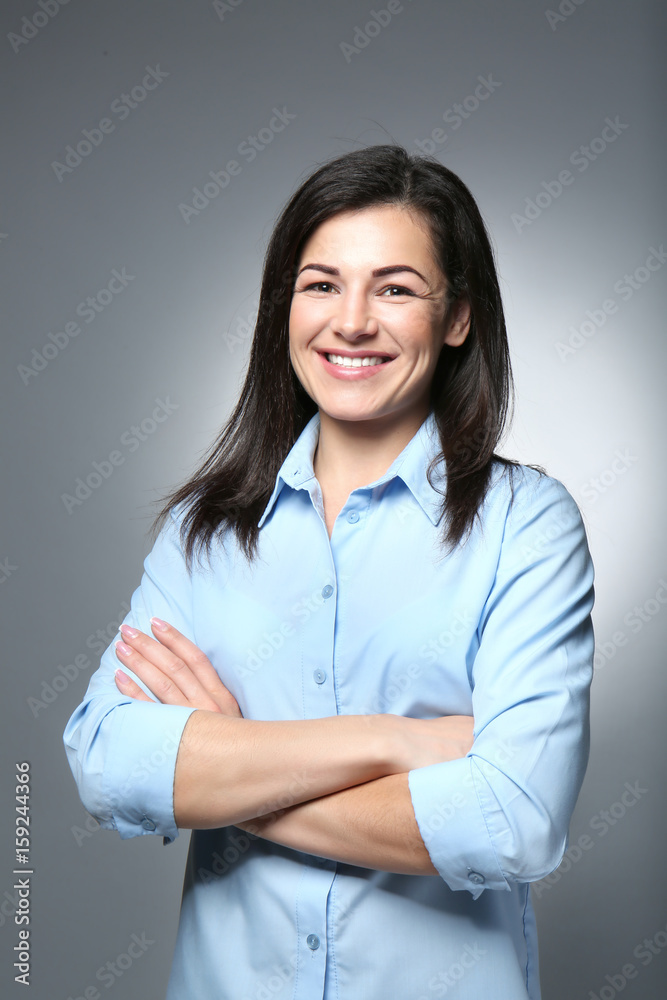 Portrait of young smiling woman with crossed hands on grey background Portrait of young smiling woman with crossed hands on grey background
