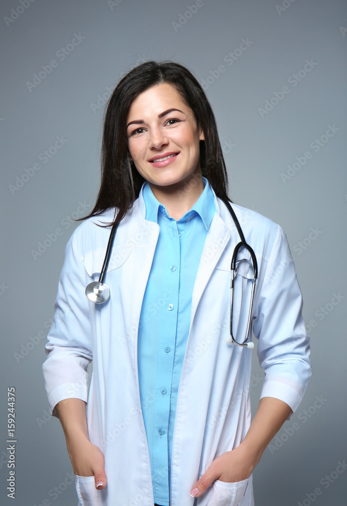 Beautiful young doctor on grey background Beautiful young doctor on grey background