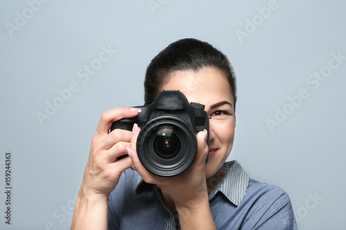Portrait of beautiful young photographer on grey background