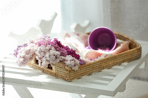 Wicker tray with beautiful lilac flowers on table