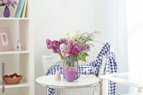 Glass vase with beautiful lilac flowers on table