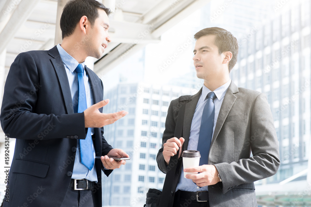 Businessmen discussing while walking to work in the morning Businessmen discussing while walking to work in the morning