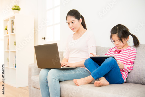 Woman and girl with laptop and digital tablet
