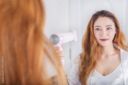woman looking in the mirror drying her hair