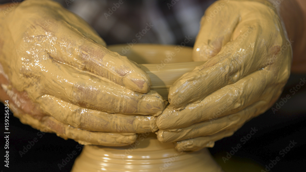 A close-up shot of a craftsman's hand crafting a pottery.
