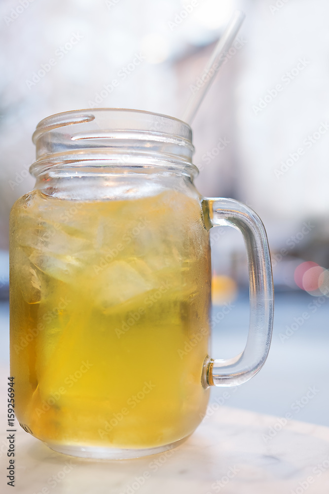 Iced tea in a mason jar with a straw. Selective focus with background blur Iced tea in a mason jar with a straw. Selective focus with background blur