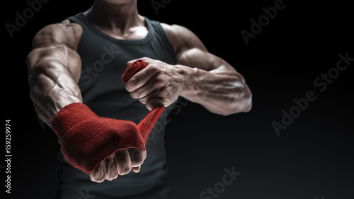 Obraz na plátně Close-up photo of strong man wrap hands on black background with copy space for