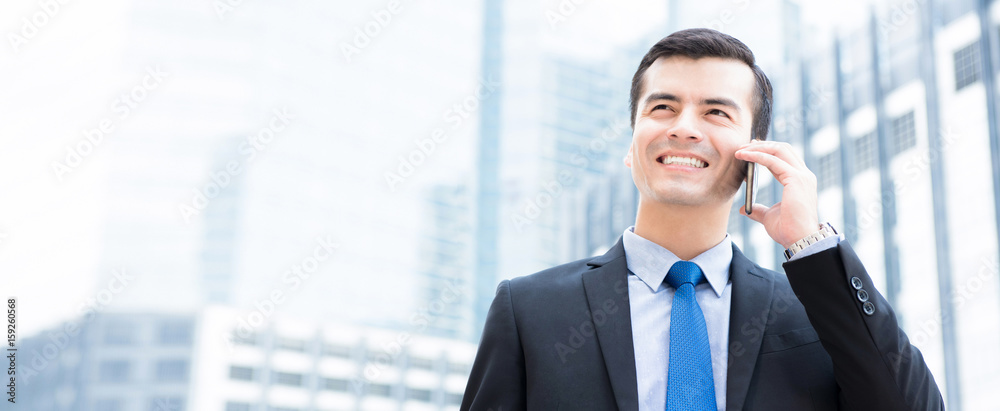 Smiling businessman calling on smartphone