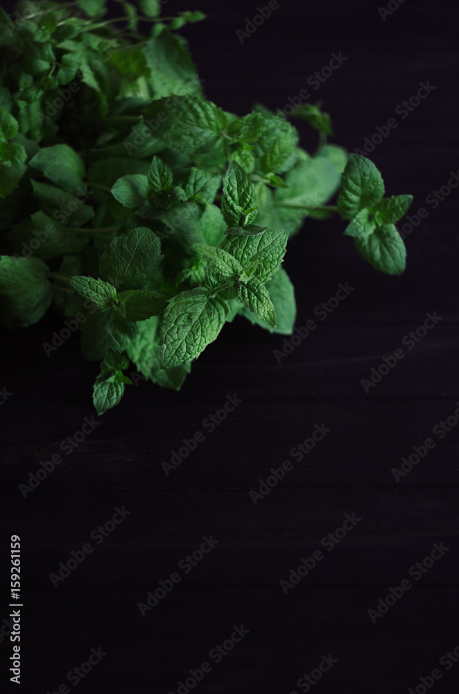 Sheaf green fresh mint closeup on rustic dark brown wooden board. Sheaf green fresh mint closeup on rustic dark brown wooden board.