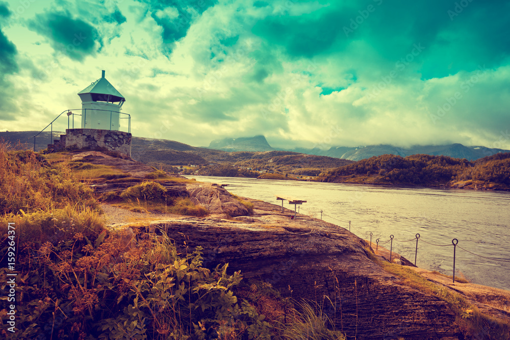 Lighthouse against dramatic cloudy sky during sunset