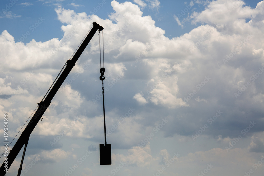 Silhouette of crane at a construction site on a background of the sky Silhouette of crane at a construction site on a background of the sky