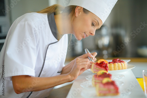 Portrait of pastry chef cutting slices of cake for serving