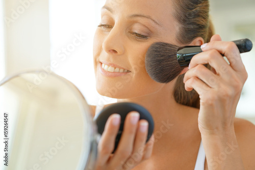 Portrait of beautiful woman putting makeup on