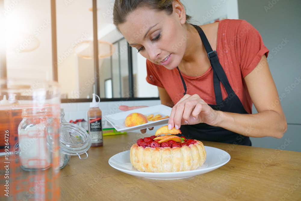 Young woman in modern kitchen baking raspberry cake