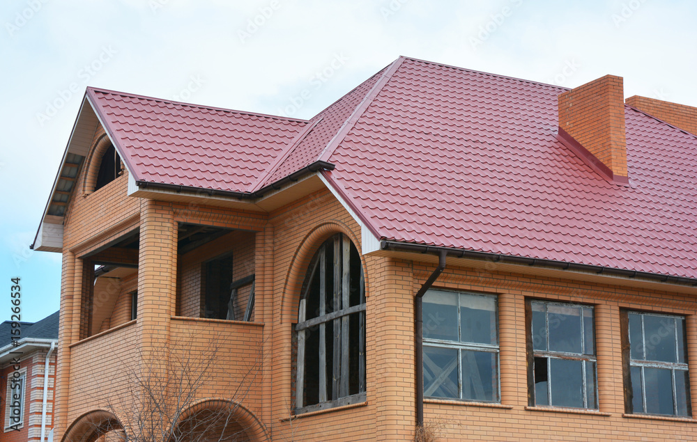 New metal roofing construction with rain gutter system guttering, brick chimney and Attic, mansard roof repair.