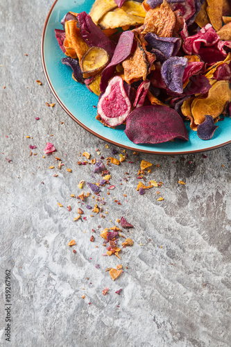 Beet and carrot salty chips in an old blue plate. Stone light background. Top view