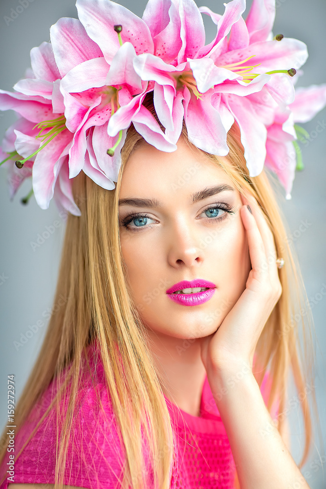Beautiful woman portrait with flowers on head. Young lady posing on grey background. Gorgeous make up. Magnetic view. Glamour lipstick.