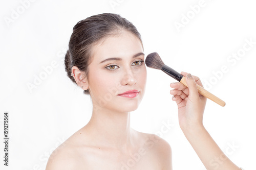 Makeup artist applies brushed at woman face. Beautiful woman face. Perfect makeup, isolated on white background, 20s year old.
